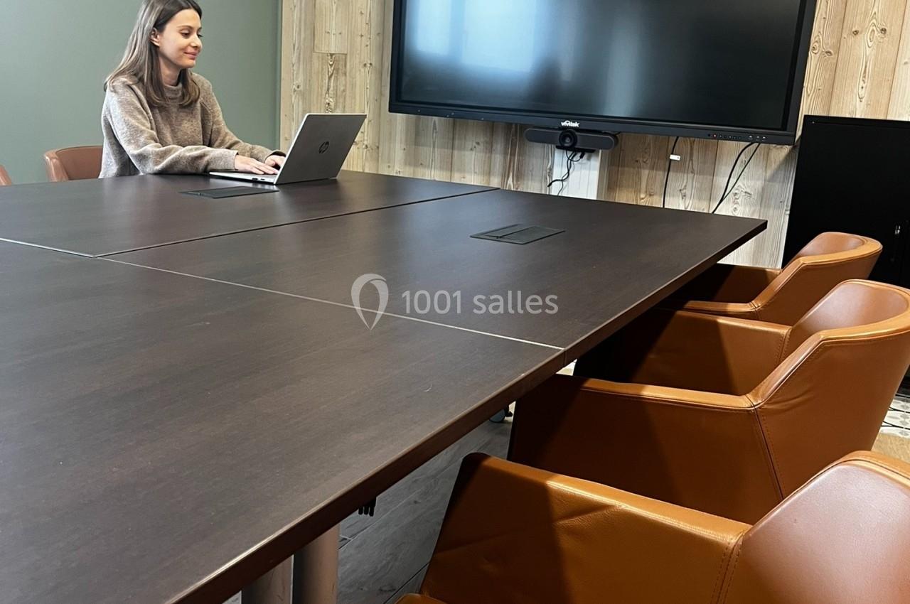 Une femme travaille sur un ordinateur portable dans une salle de réunion avec une grande table, des chaises en cuir et un…