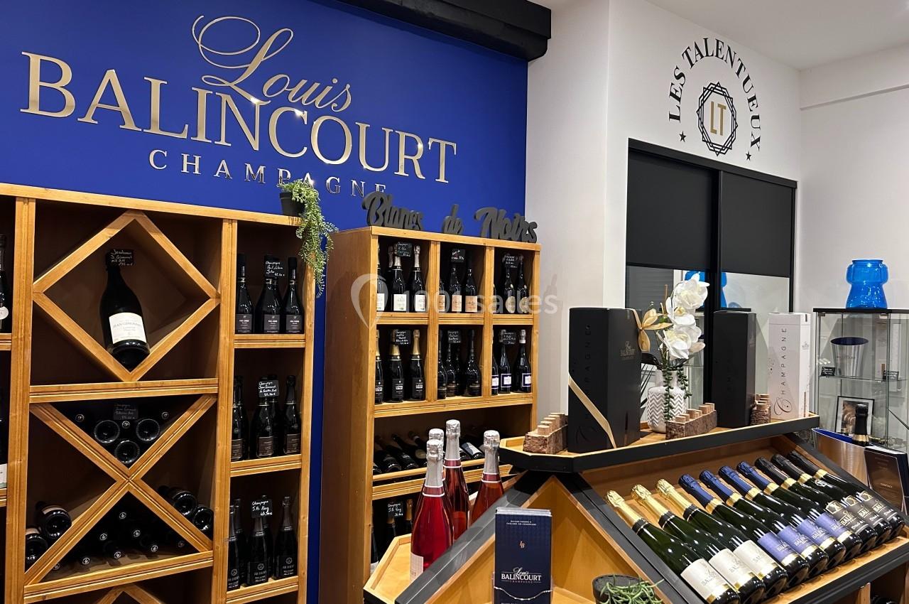 Rayonnages de bouteilles de champagne et de vin exposés dans une boutique avec une enseigne ’Louis Balincourt’.