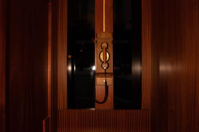 Une main tenant un verre de vin blanc dans un environnement sombre, avec des personnes et une lampe en arrière-plan.