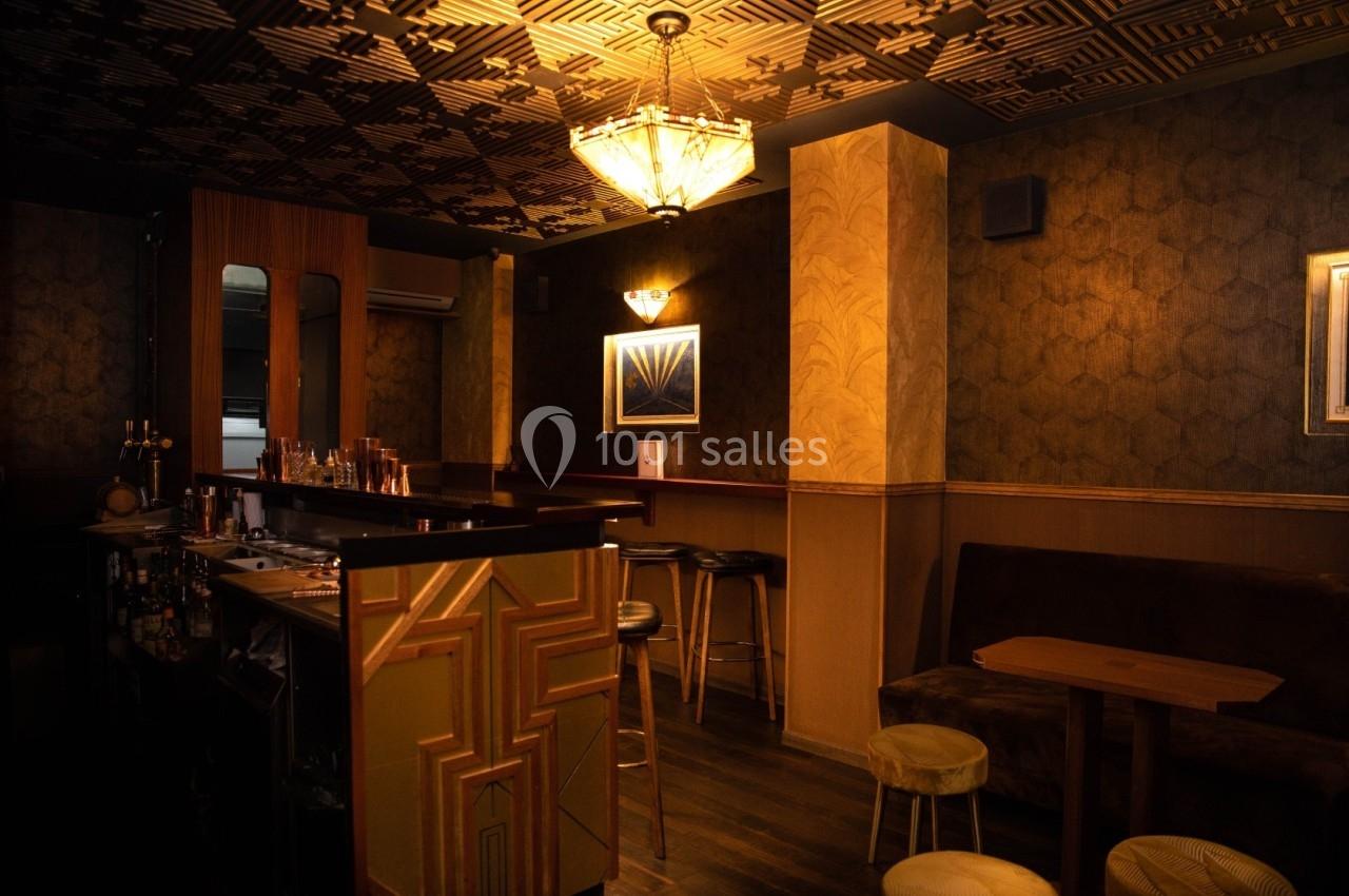 Intérieur d'un bar à l'ambiance feutrée avec éclairage tamisé, décor art déco et mobilier en bois et velours.