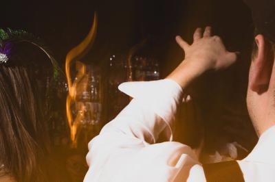 Une femme assise dans un bar sombre tient un menu près d'un cocktail rouge servi dans un verre élégant.