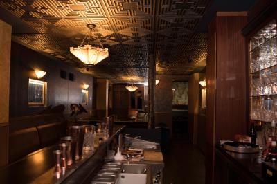 Une femme assise dans un bar sombre tient un menu près d'un cocktail rouge servi dans un verre élégant.