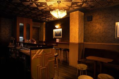 Une femme assise dans un bar sombre tient un menu près d'un cocktail rouge servi dans un verre élégant.