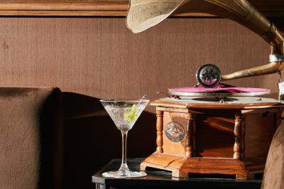 Une femme assise dans un bar sombre tient un menu près d'un cocktail rouge servi dans un verre élégant.