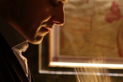 Une femme assise dans un bar sombre tient un menu près d'un cocktail rouge servi dans un verre élégant.