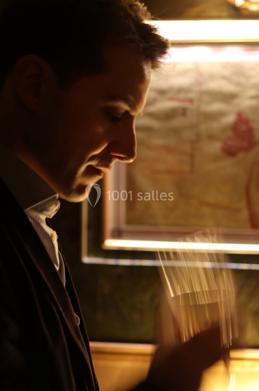 Un homme de profil tenant un verre, éclairé par une lumière chaude, avec un cadre flou en arrière-plan.