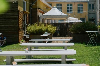 Salle élégante avec parquet, comptoir noir, lustre central et grandes fenêtres encadrées de rideaux.