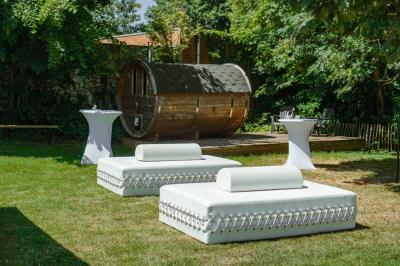 Salle élégante avec parquet, comptoir noir, lustre central et grandes fenêtres encadrées de rideaux.