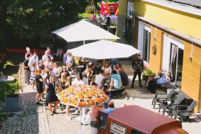 Salle élégante avec parquet, comptoir noir, lustre central et grandes fenêtres encadrées de rideaux.