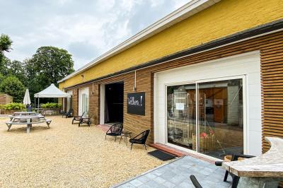 Salle élégante avec parquet, comptoir noir, lustre central et grandes fenêtres encadrées de rideaux.