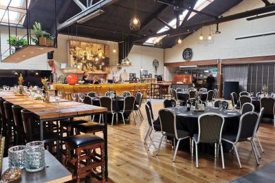 Salle élégante avec parquet, comptoir noir, lustre central et grandes fenêtres encadrées de rideaux.
