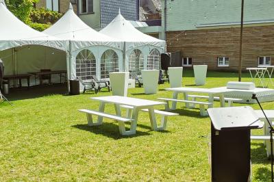 Salle élégante avec parquet, comptoir noir, lustre central et grandes fenêtres encadrées de rideaux.