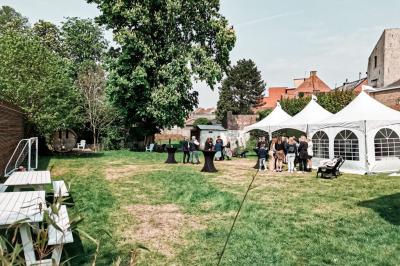 Salle élégante avec parquet, comptoir noir, lustre central et grandes fenêtres encadrées de rideaux.