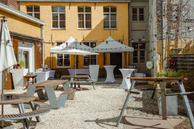 Salle élégante avec parquet, comptoir noir, lustre central et grandes fenêtres encadrées de rideaux.