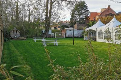 Salle élégante avec parquet, comptoir noir, lustre central et grandes fenêtres encadrées de rideaux.