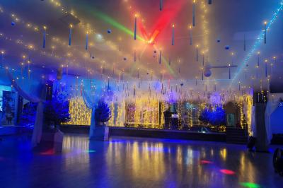 Salle vide avec un sol en parquet sombre, éclairée par la lumière naturelle entrant par de grandes fenêtres.