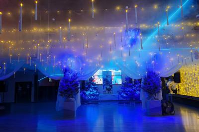 Salle vide avec un sol en parquet sombre, éclairée par la lumière naturelle entrant par de grandes fenêtres.