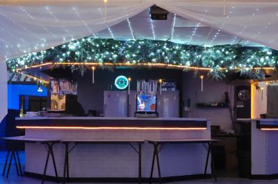 Salle vide avec un sol en parquet sombre, éclairée par la lumière naturelle entrant par de grandes fenêtres.