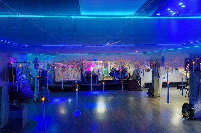 Salle vide avec un sol en parquet sombre, éclairée par la lumière naturelle entrant par de grandes fenêtres.