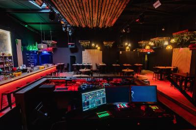 Couloir sombre avec éclairage violet, menant à un lavabo éclairé par un miroir rond lumineux.