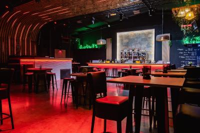 Couloir sombre avec éclairage violet, menant à un lavabo éclairé par un miroir rond lumineux.