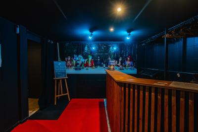 Terrasse extérieure couverte avec éclairage suspendu, séparations en bois, tables hautes et plantes décoratives.