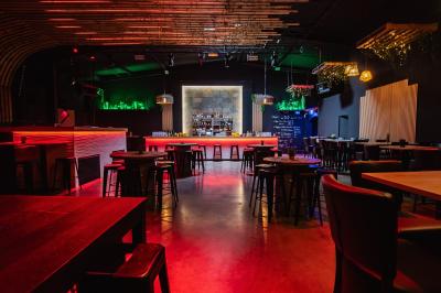 Terrasse extérieure couverte avec éclairage suspendu, séparations en bois, tables hautes et plantes décoratives.