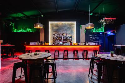 Terrasse extérieure couverte avec éclairage suspendu, séparations en bois, tables hautes et plantes décoratives.