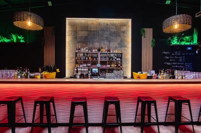 Terrasse extérieure couverte avec éclairage suspendu, séparations en bois, tables hautes et plantes décoratives.