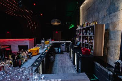 Terrasse extérieure couverte avec éclairage suspendu, séparations en bois, tables hautes et plantes décoratives.