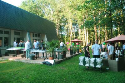 Salle décorée avec des ballons bleus, blancs et dorés, tables dressées et groupe de personnes discutant debout.