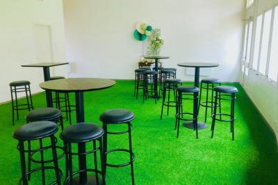 Salle décorée avec des ballons bleus, blancs et dorés, tables dressées et groupe de personnes discutant debout.