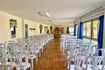 Salle décorée avec des ballons bleus, blancs et dorés, tables dressées et groupe de personnes discutant debout.