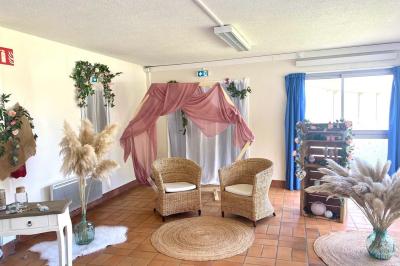 Salle décorée avec des ballons bleus, blancs et dorés, tables dressées et groupe de personnes discutant debout.