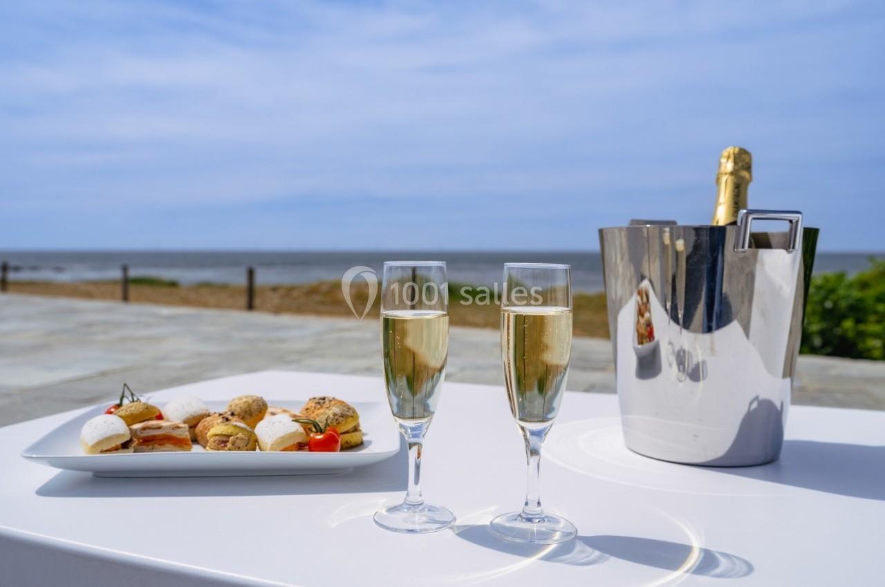 Deux coupes de champagne, un plateau de mignardises et un seau à glace sur une table face à la mer.