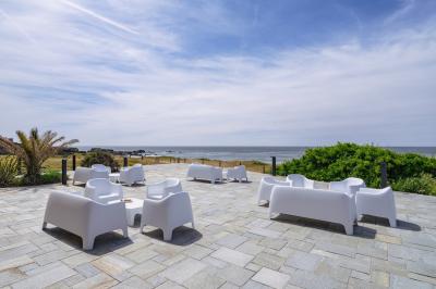 Vue aérienne d'une plage bordée de falaises avec des maisons et un parking à proximité, dans un paysage côtier.