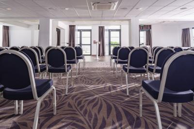 Vue aérienne d'une plage bordée de falaises avec des maisons et un parking à proximité, dans un paysage côtier.