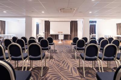Vue aérienne d'une plage bordée de falaises avec des maisons et un parking à proximité, dans un paysage côtier.