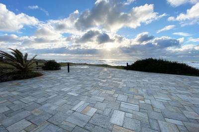 Vue aérienne d'une plage bordée de falaises avec des maisons et un parking à proximité, dans un paysage côtier.