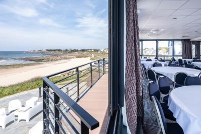 Vue aérienne d'une plage bordée de falaises avec des maisons et un parking à proximité, dans un paysage côtier.