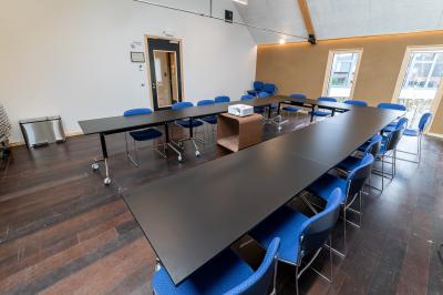 Bâtiment moderne avec façade en verre et briques, entouré de végétation et d'une allée pavée.