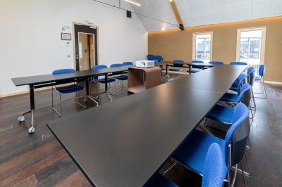 Bâtiment moderne avec façade en verre et briques, entouré de végétation et d'une allée pavée.