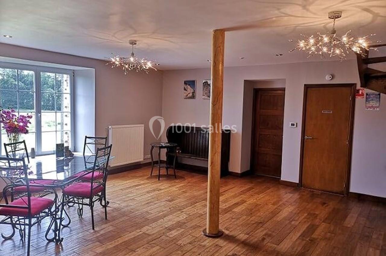 Salle lumineuse avec parquet, table en verre entourée de chaises, banquette contre le mur et décorations modernes.