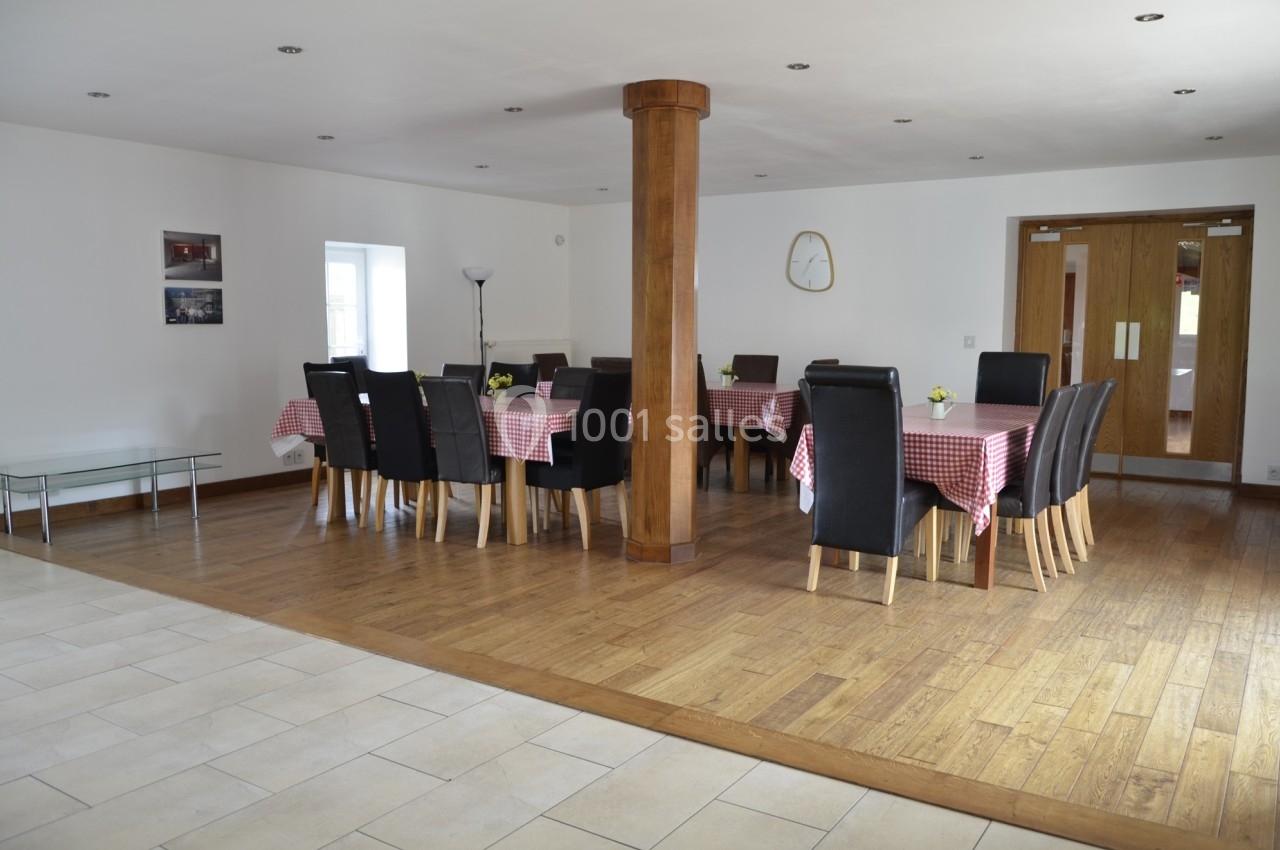 Salle à manger lumineuse avec tables recouvertes de nappes à carreaux rouges, chaises noires et sol en bois.