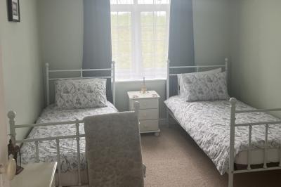 Deux femmes souriantes posent devant une voiture grise marquée ’France Bleu’, stationnée devant un bâtiment en pierre.