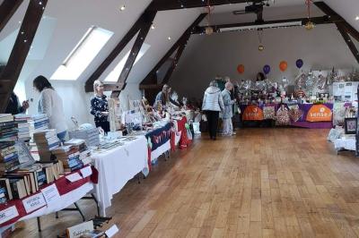 Deux femmes souriantes posent devant une voiture grise marquée ’France Bleu’, stationnée devant un bâtiment en pierre.