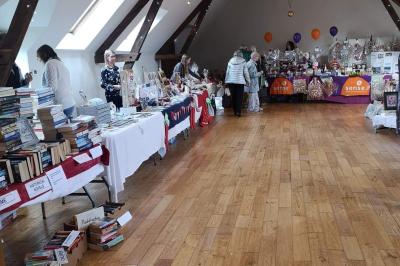 Deux femmes souriantes posent devant une voiture grise marquée ’France Bleu’, stationnée devant un bâtiment en pierre.