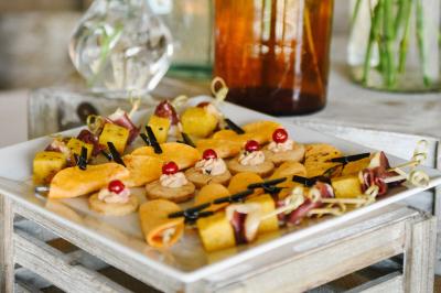 Gâteau de fête décoré de bougies scintillantes, entouré de desserts et de convives en arrière-plan flou.