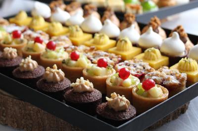 Gâteau de fête décoré de bougies scintillantes, entouré de desserts et de convives en arrière-plan flou.