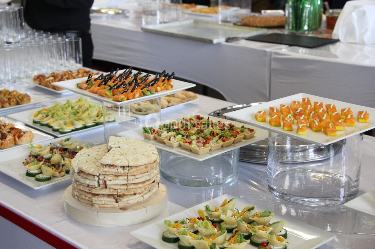 Buffet de réception avec divers amuse-bouches, tartes salées, canapés et verrines disposés sur des plateaux.